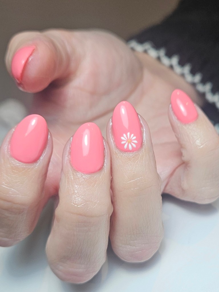 Coral pink builder gel nails with daisy nail art.